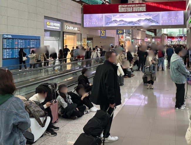 25일 오전 인천국제공항 제2여객터미널에서 출국심사를 마친 승객들이 바닥에 앉아 항공편 탑승을 기다리고 있다. /독자 제공